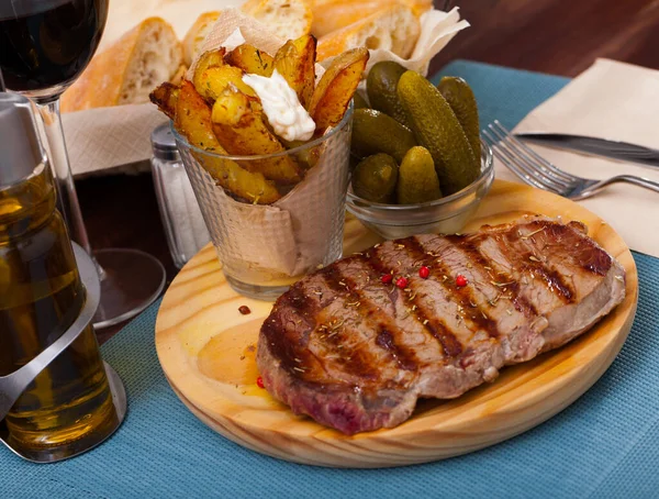 Entrrecote de carne com temperos em uma tábua redonda de madeira — Fotografia de Stock