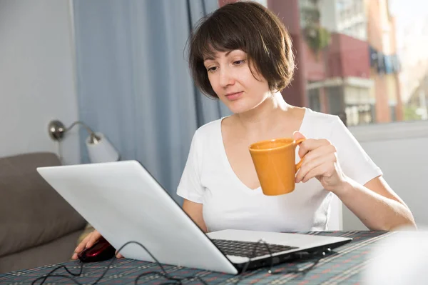 Relaxamento da mulher em casa e usando laptop — Fotografia de Stock