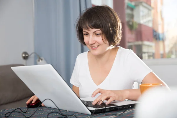 Frau entspannt sich zu Hause und nutzt Laptop — Stockfoto