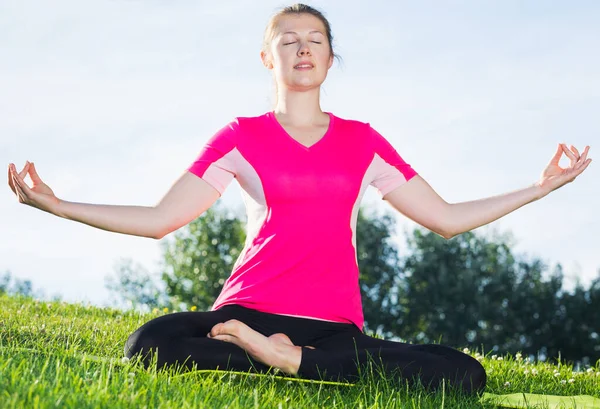 Female 26-32 years old in pink T-shirt is sitting and meditating — Stock Photo, Image