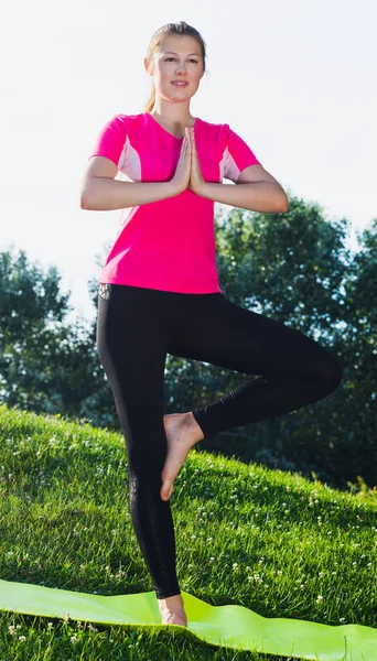 Sonriente hembra adulta con camiseta rosa se queda y practica meditación —  Fotos de Stock