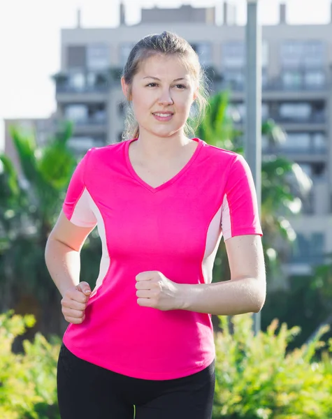 Ragazza in rosa T-shirt sta facendo jogging — Foto Stock