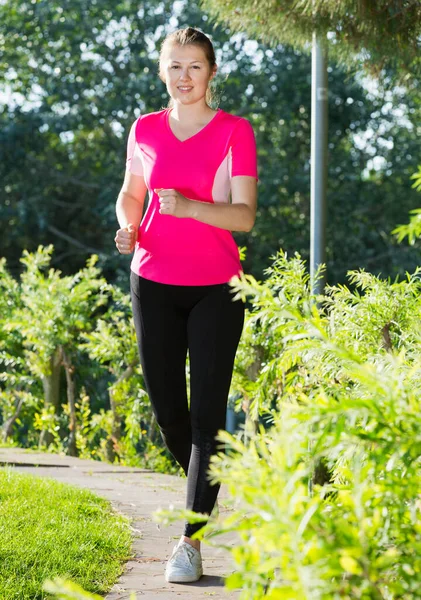 Жінка в рожевій футболці біжить — стокове фото