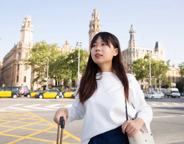 Boldog fiatal kínai turista sétál a városban az utazótáskával — Stock Fotó