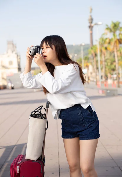 Ung kinesisk kvinna resenär promenader med bagage runt staden, gör foto av sevärdheter — Stockfoto
