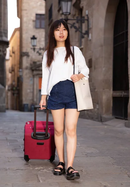 Boldog fiatal kínai turista sétál a városban az utazótáskával — Stock Fotó