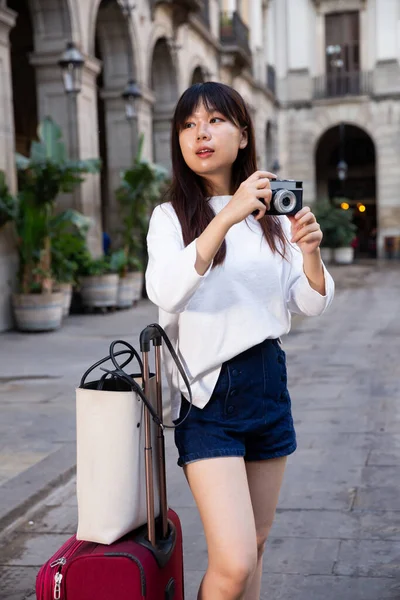 Mosolygó fiatal lány kezében kamera és fényképezés a városban — Stock Fotó