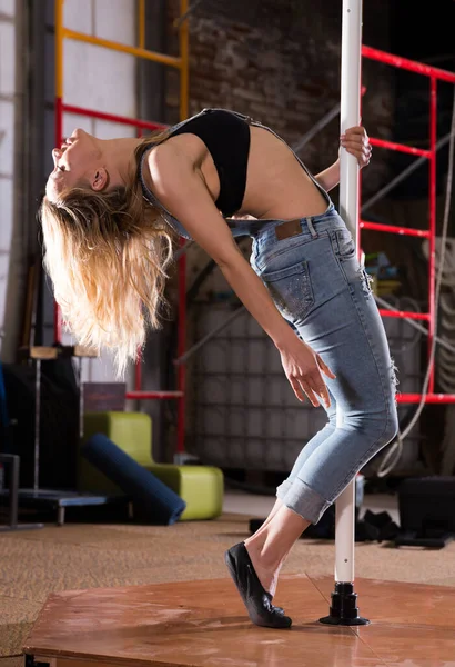 Сексуальна молода жінка в рваних джинсах практикує полюс танцює — стокове фото