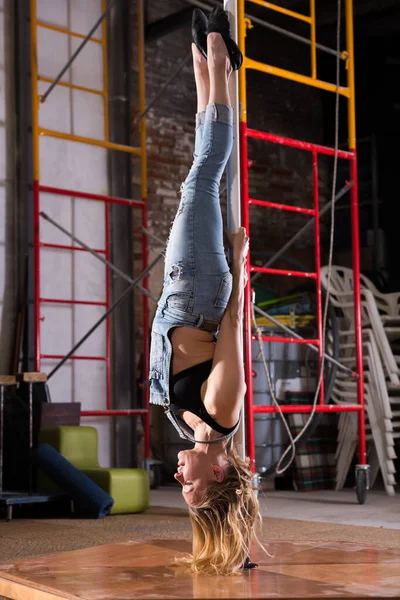 Jovem mulher em jeans rasgado realizando pole dance — Fotografia de Stock