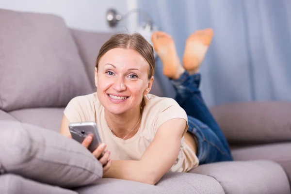 Kvinna som ligger på soffan med telefon — Stockfoto