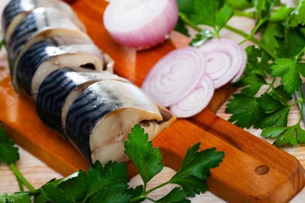 Solená makrela se zelení a cibulí na dřevěné desce — Stock fotografie