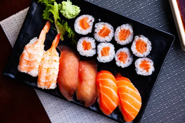 Verschillende sushi geserveerd op zwarte plaat. Japans eten — Stockfoto