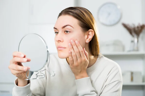 Glimlachende vrouw kijkt op haar huid in de spiegel — Stockfoto