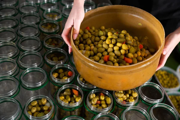 Female hands filling glass jars with pickled olives — Stock Photo, Image