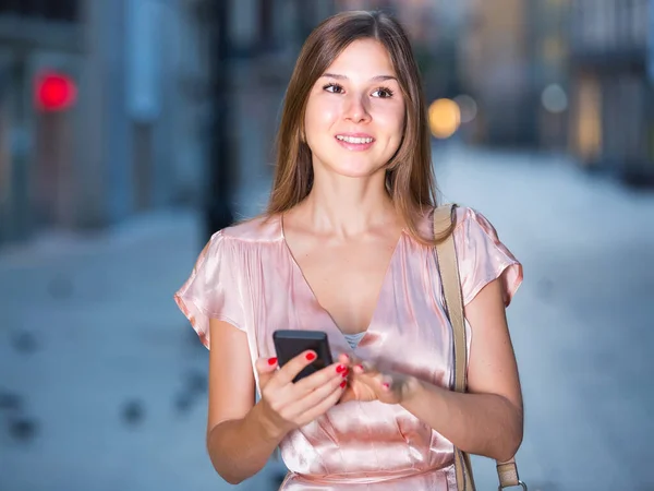 Kobieta patrząc na telefon w rękach i czat w mieście — Zdjęcie stockowe