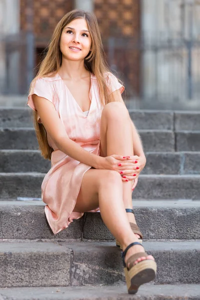身着玫瑰花裙的年轻女子坐在城市里 — 图库照片