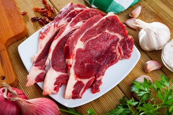 Carne cruda entrecotes con perejil, cebolla, ajo y especias —  Fotos de Stock