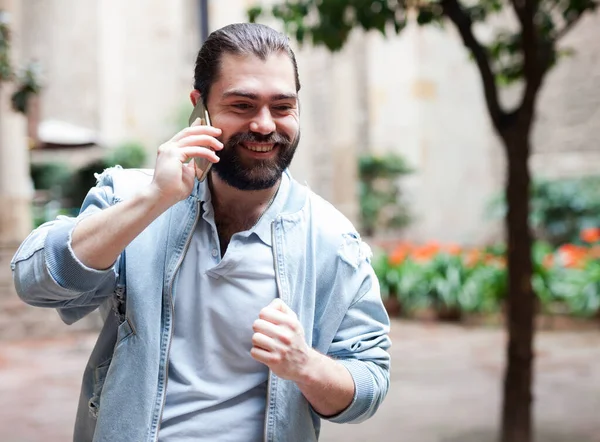 Pozitif adam sokakta dikiliyor ve akıllı telefonla konuşuyor. — Stok fotoğraf