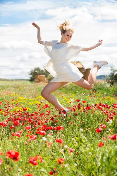 Jolie jeune femme sautant dans le champ de pavot — Photo