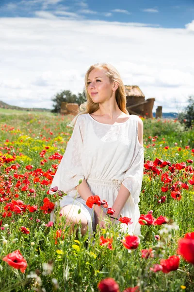 Retrato de mujer joven en vestido blanco posando en planta de amapolas — Foto de Stock