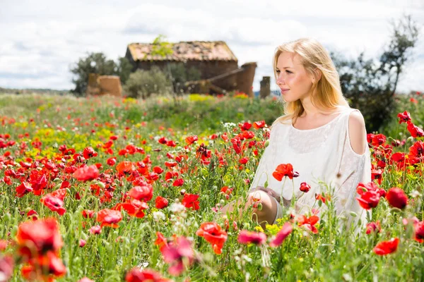 Vacker ung kvinna i vit klänning i vallmo fält av vilda blommor — Stockfoto