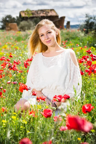 Porträt einer jungen Frau im weißen Kleid, die in einer Mohnpflanze posiert — Stockfoto