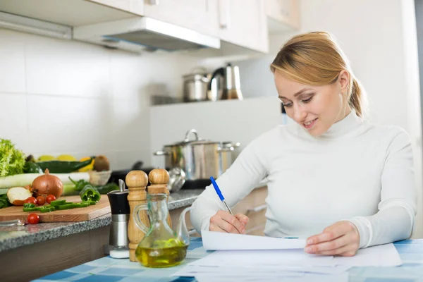 Bonne femme au foyer avec des documents dans la cuisine — Photo