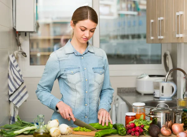 Το χαρούμενο θηλυκό κόβει λαχανικά για σαλάτα στην κουζίνα στο σπίτι. — Φωτογραφία Αρχείου
