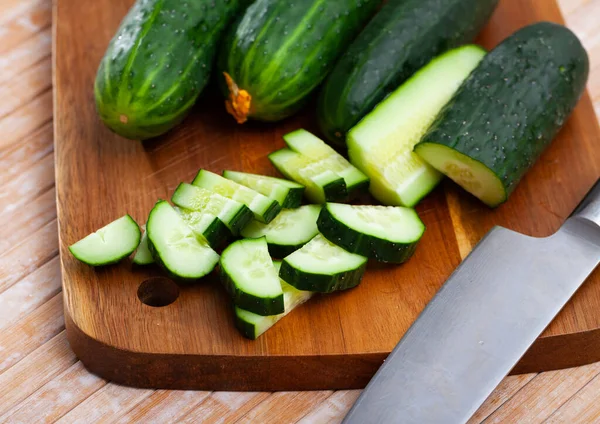 Pepinos en rodajas sobre mesa de madera, ingredientes alimentarios — Foto de Stock