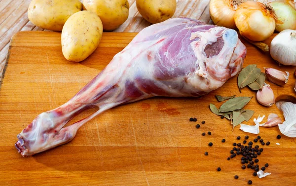 Raw lamb leg with potatoes and condiments — Stock Photo, Image