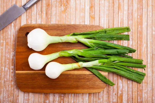 Hele groene jonge uienbollen op houten bureau — Stockfoto