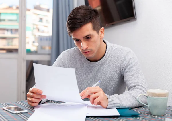 Homme assis à table à la maison calculant les finances et les factures domestiques — Photo