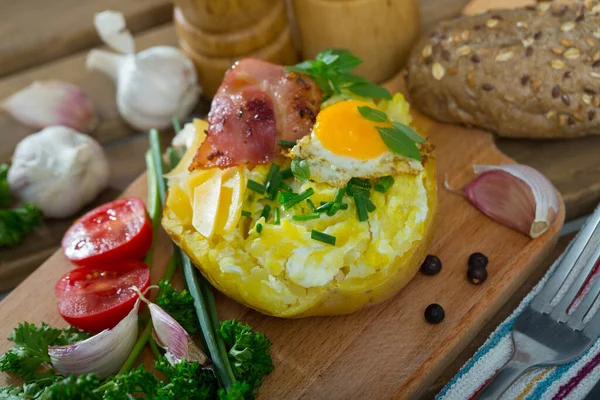 Baked potatoes with fried egg, bacon, cheese, scallions — Stock Photo, Image