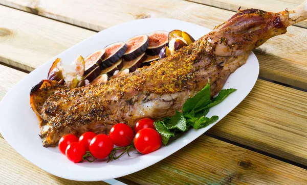 Baked shoulder of lamb served with fig, feta cheese, herbs and cherry tomatoes at plate — Stock Photo, Image