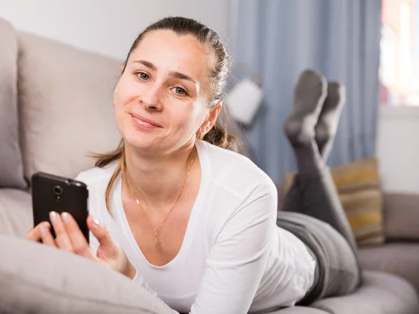 Frau nutzt Smartphone im Wohnzimmer — Stockfoto