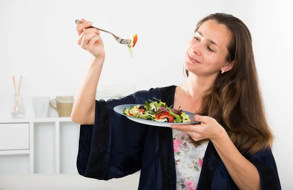 Mladá hezká žena jíst zeleninový salát z platón v posteli — Stock fotografie