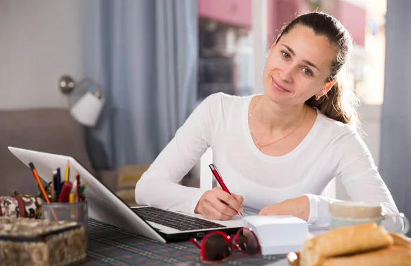 Young woman sitting at table at home calculating domestic finances