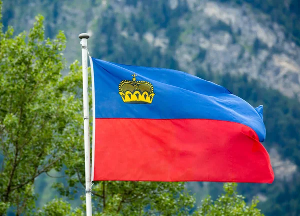 Bandera de Liechtenstein ondeando sobre fondo de montaña — Foto de Stock