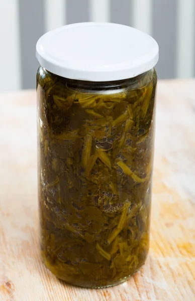 Canned green spinach in glass jar on wooden surface — Stock Photo, Image