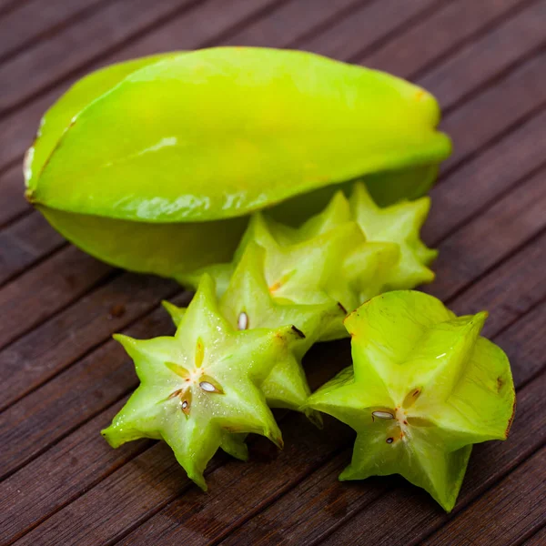 Gesneden carambolen en hele vruchten op houten tafel — Stockfoto