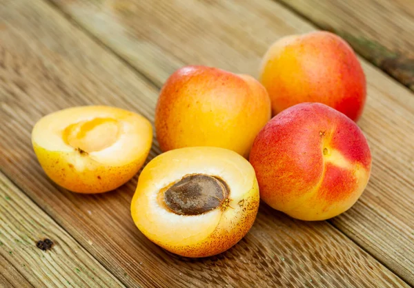 Rijp hele abrikozen en helften op houten ondergrond — Stockfoto