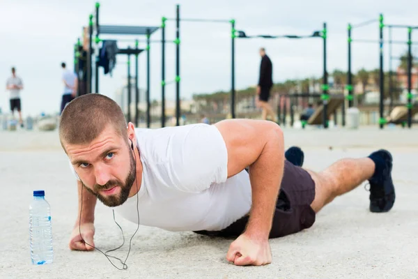 Man performs pushup on sportsground — стоковое фото