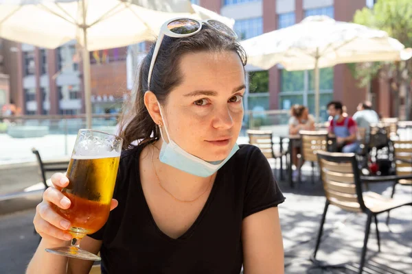 Donna in maschera medica protettiva con bicchiere di birra al bar — Foto Stock