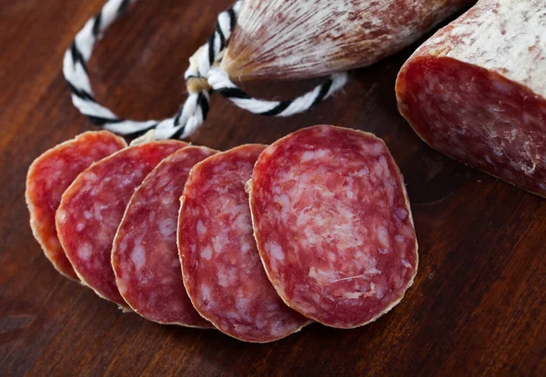 Spanish longaniza salami sausages cut in slices on a woodefn desk — Stock Photo, Image