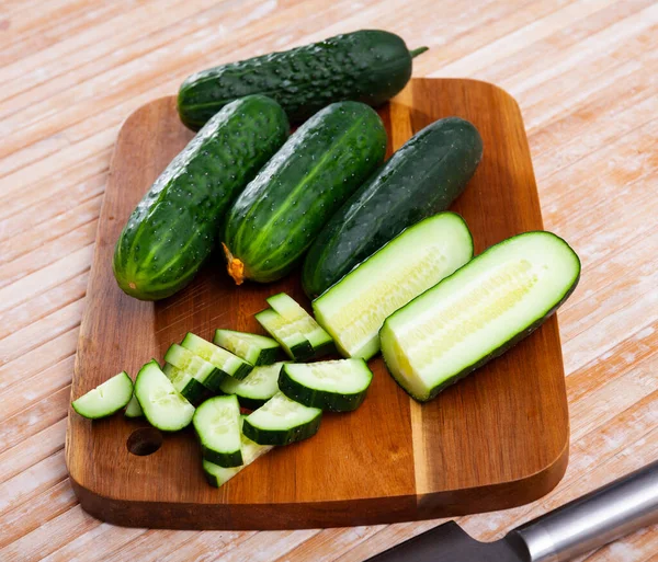 Pepinos y cuchillo en tabla de cortar de madera — Foto de Stock