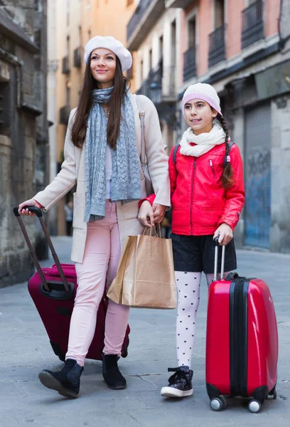 Kvinna med dotter promenader med väskor — Stockfoto