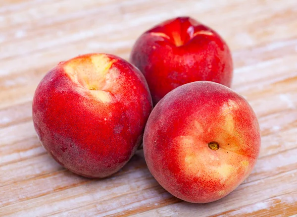 Buah persik matang yang lezat di permukaan kayu di dapur — Stok Foto