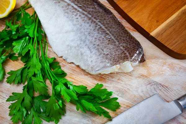 Fillet van rauwe kabeljauw op een houten ondergrond met knoflook en groente — Stockfoto