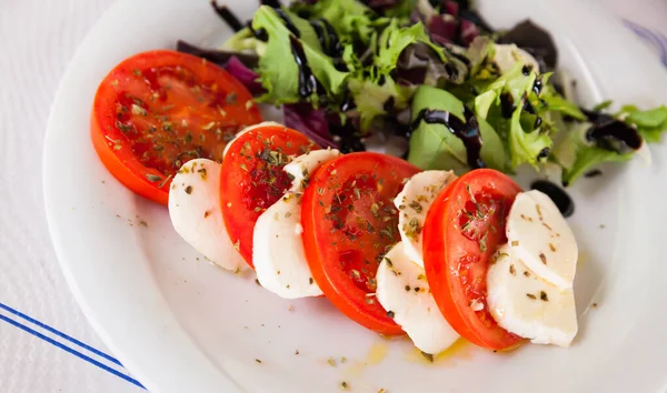 Frischer italienischer Caprese-Salat mit Mozzarella und Tomaten auf weißem Teller — Stockfoto