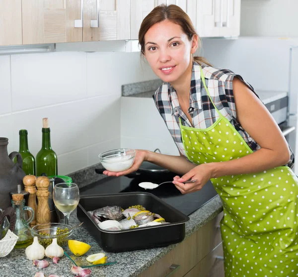 Donna che cucina pesce con limone — Foto Stock